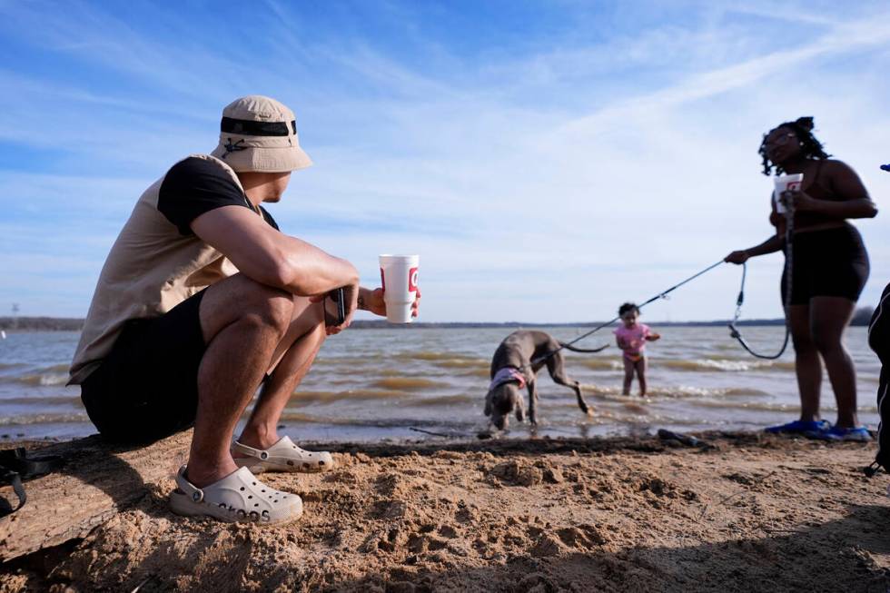 FILE - Victor Marcano, left, sits on a log as he watches his daughter Zhamira Marcano, 3, stand ...