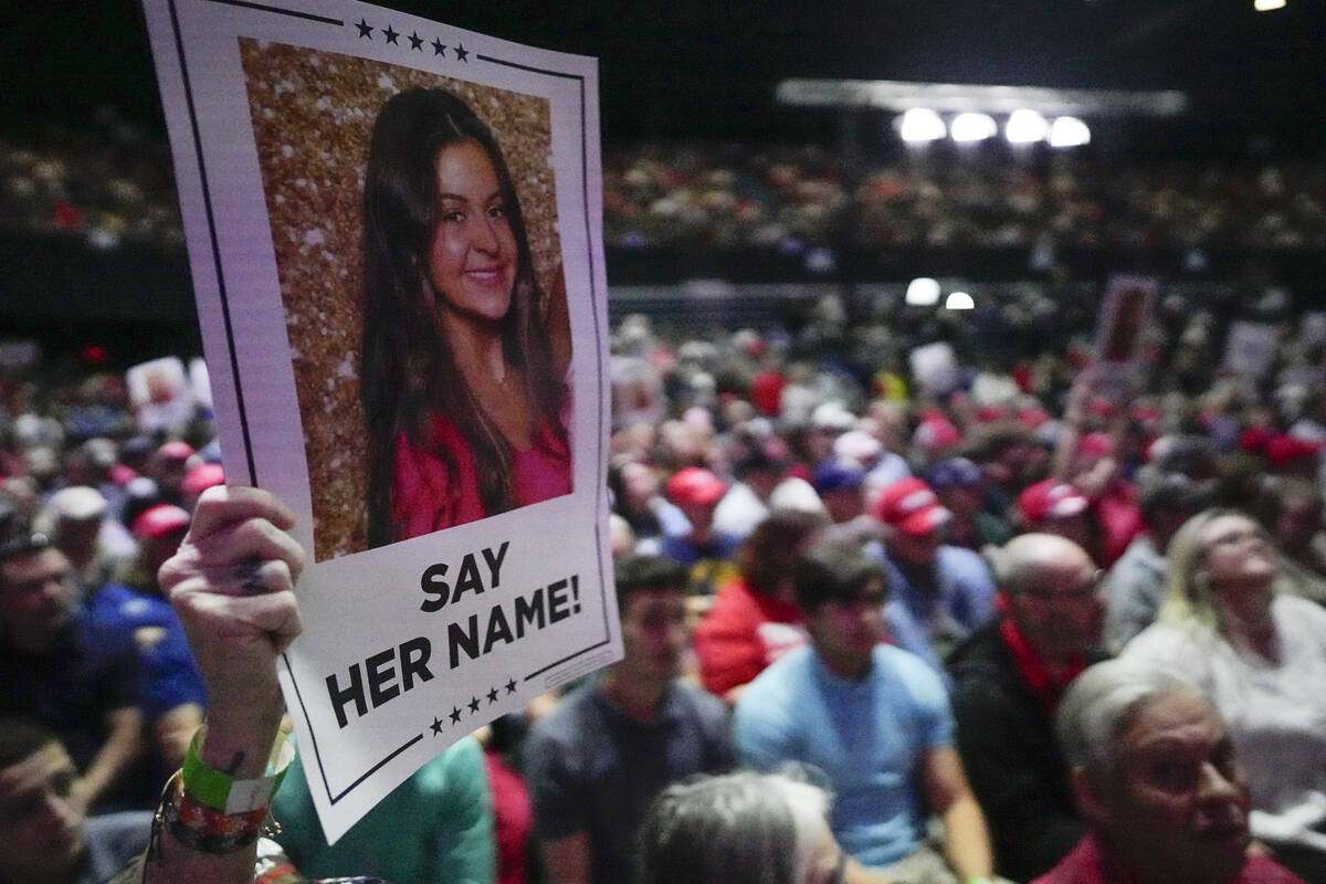 A supporter holds a oster with a photo of Laken Riley before Republican presidential candidate ...