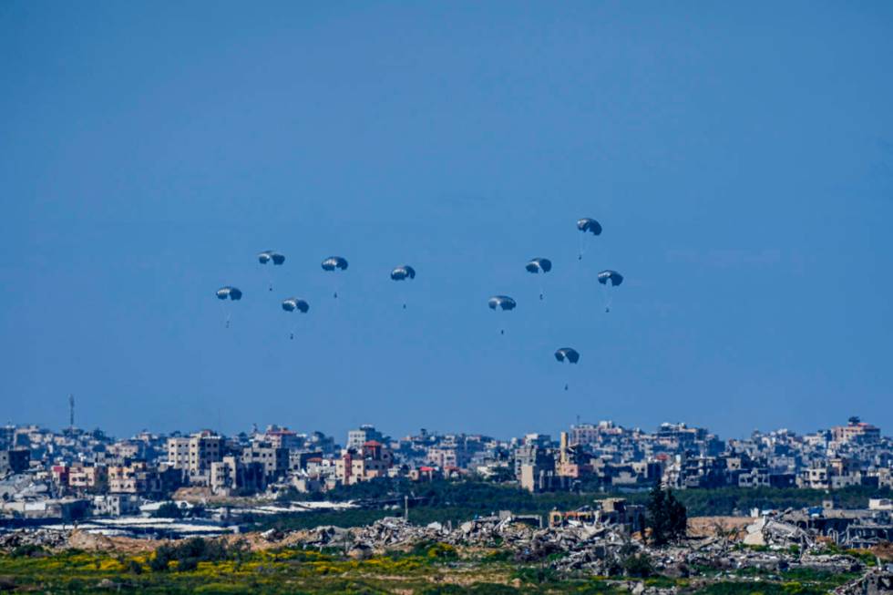 Parachutes drop supplies into the northern Gaza Strip, as seen from southern Israel , Sunday, M ...