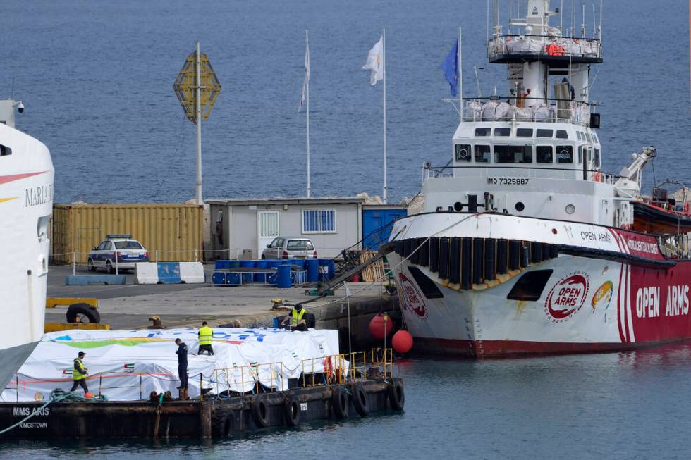 Port staffers prepare the aid on a platform near to the docked ship belonging to the Open Arms ...