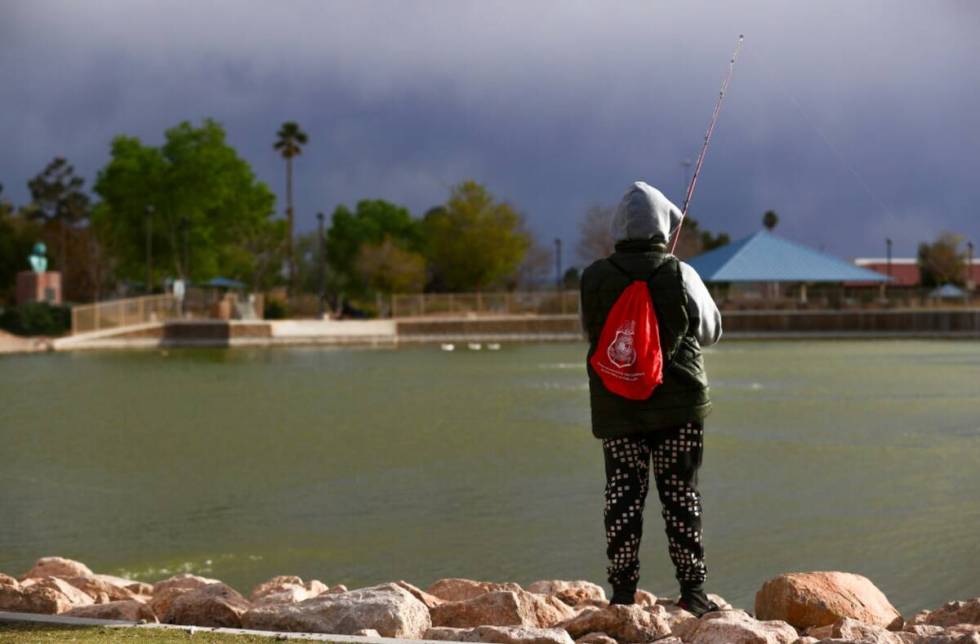 A fisherman waits for a bite as stormy skies loom over Lorenzi Park on Thursday, March 14, 2024 ...