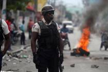 A police stands near a burning barricade set up by protesters in Port-au-Prince, Haiti, Monday, ...