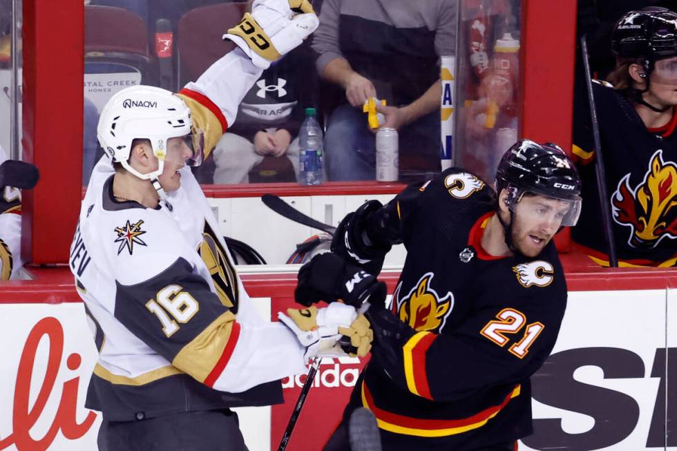 Vegas Golden Knights' Pavel Dorofeyev, left, battles with Calgary Flames' Kevin Rooney, right, ...