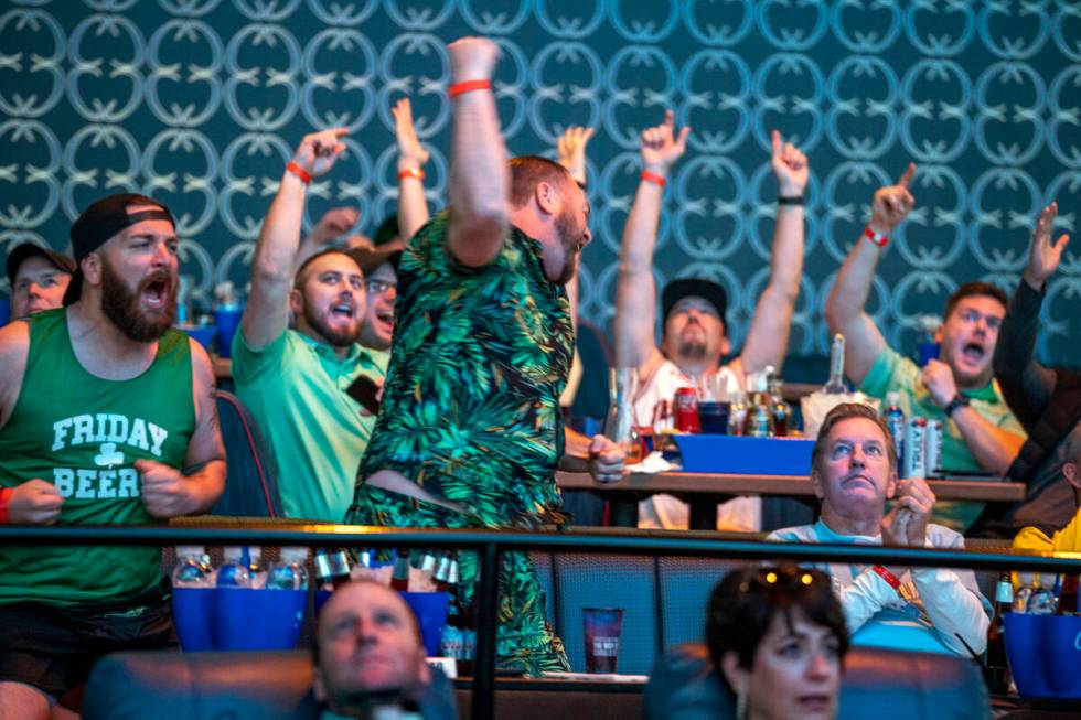 Derek Kramer, center, and his brother Cory, both from California, react with other fans to a ga ...