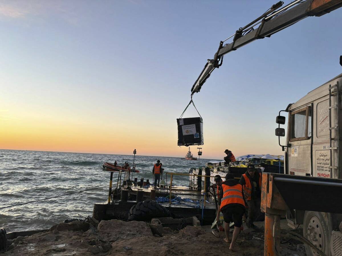 This photo provided by World Central Kitchen shows a crane unloading food packages over a makes ...