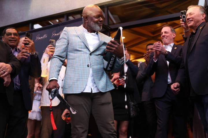 Emmitt Smith, a professional football legend, sabers a bottle of champagne during an opening ni ...