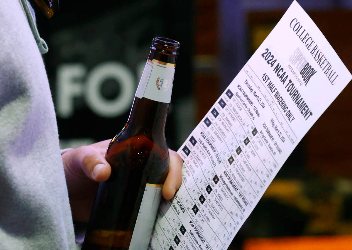 A man holds a betting sheet as he waits in line to bet on the NCAA basketball tournament at Wes ...