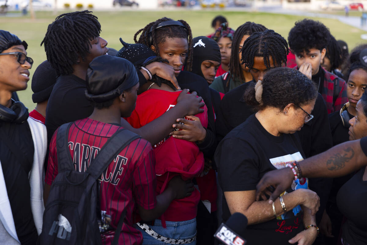 Friends and family embrace during a vigil in memory of Devin Heath, 17, who died after being hi ...