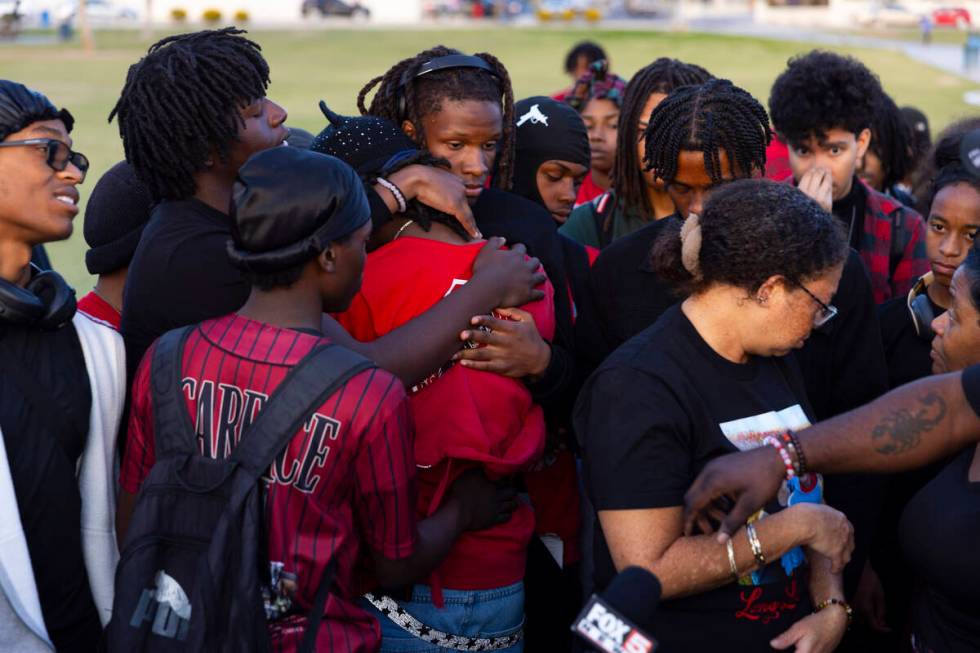 Friends and family embrace during a vigil in memory of Devin Heath, 17, who died after being hi ...