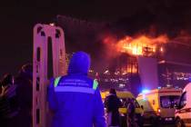 A medic stands near ambulances parked outside the burning building of the Crocus City Hall on t ...