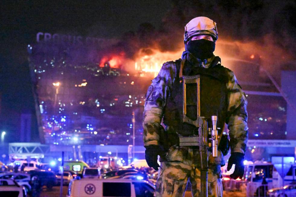 A Russian Rosguardia (National Guard) servicemen secures an area as a massive blaze seen over t ...