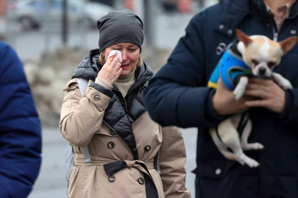 A woman reacts as she comes to place flowers at the fence next to the Crocus City Hall, on the ...