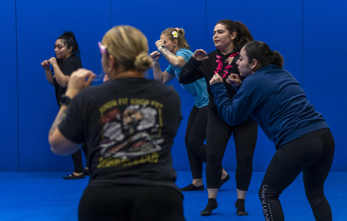 Attendees finish a maneuver in a defensive stance while learning defensive tactics with the Met ...