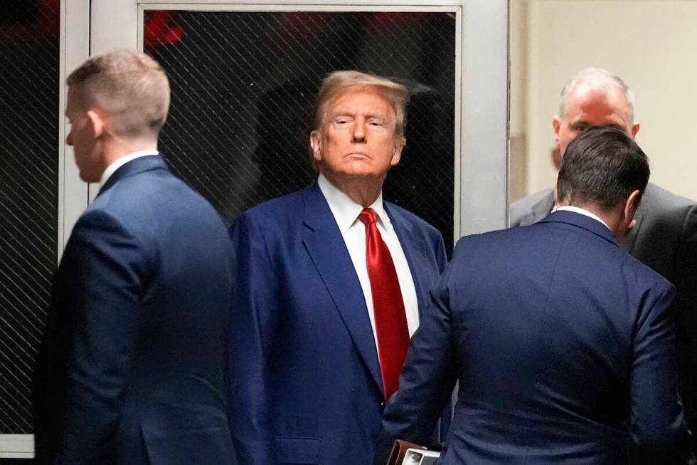 Former President Donald Trump, center, leaves a pre-trial hearing during a recess with his defe ...