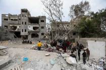 People inspect damage and search damaged buildings following Israeli air strikes on March 29, 2 ...