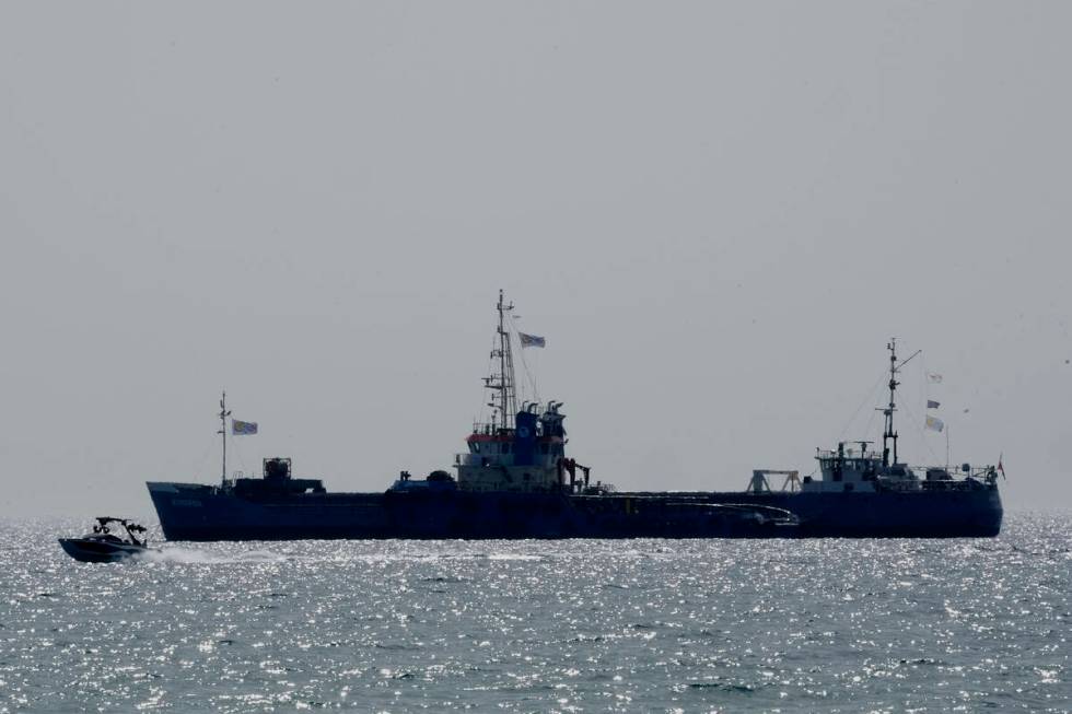 A boat passes near a ship loaded with tons of canned food destined for Gaza rests in waters jus ...