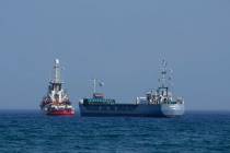 A cargo ship, right, and a ship belonging to the Open Arms aid group, are loaded with 240 tons ...