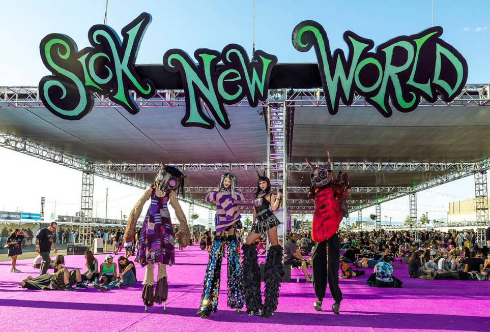 Stilt walkers in costume await photo opportunities during the Sick New World festival at the La ...