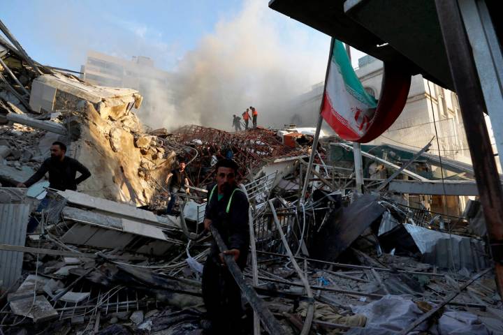 Emergency services work at a building hit by an air strike in Damascus, Syria, Monday, April 1, ...