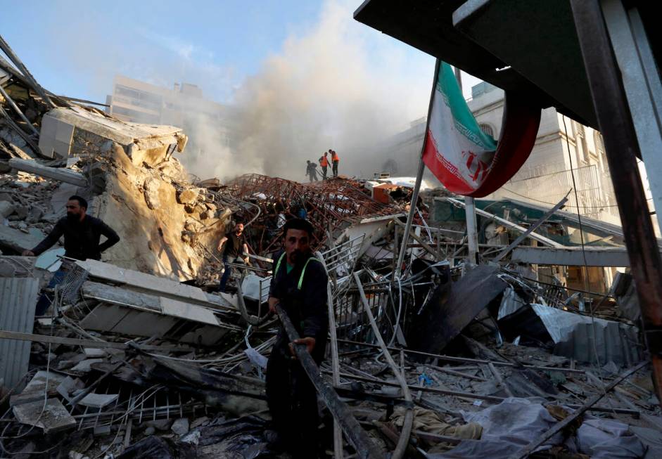 Emergency services work at a building hit by an air strike in Damascus, Syria, Monday, April 1, ...