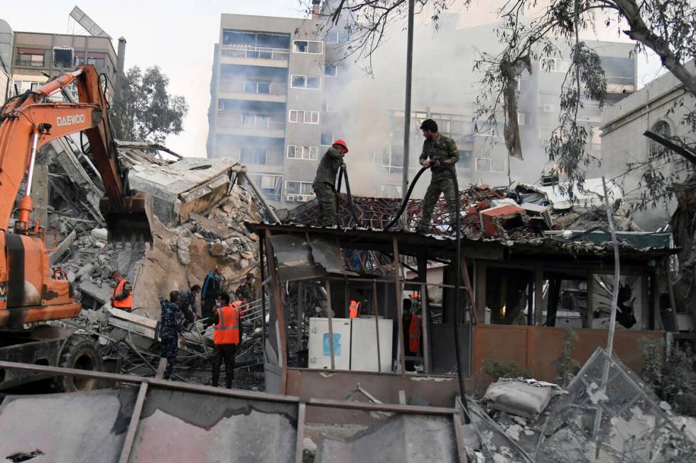 In this photo released by the official Syrian state news agency SANA, emergency service workers ...