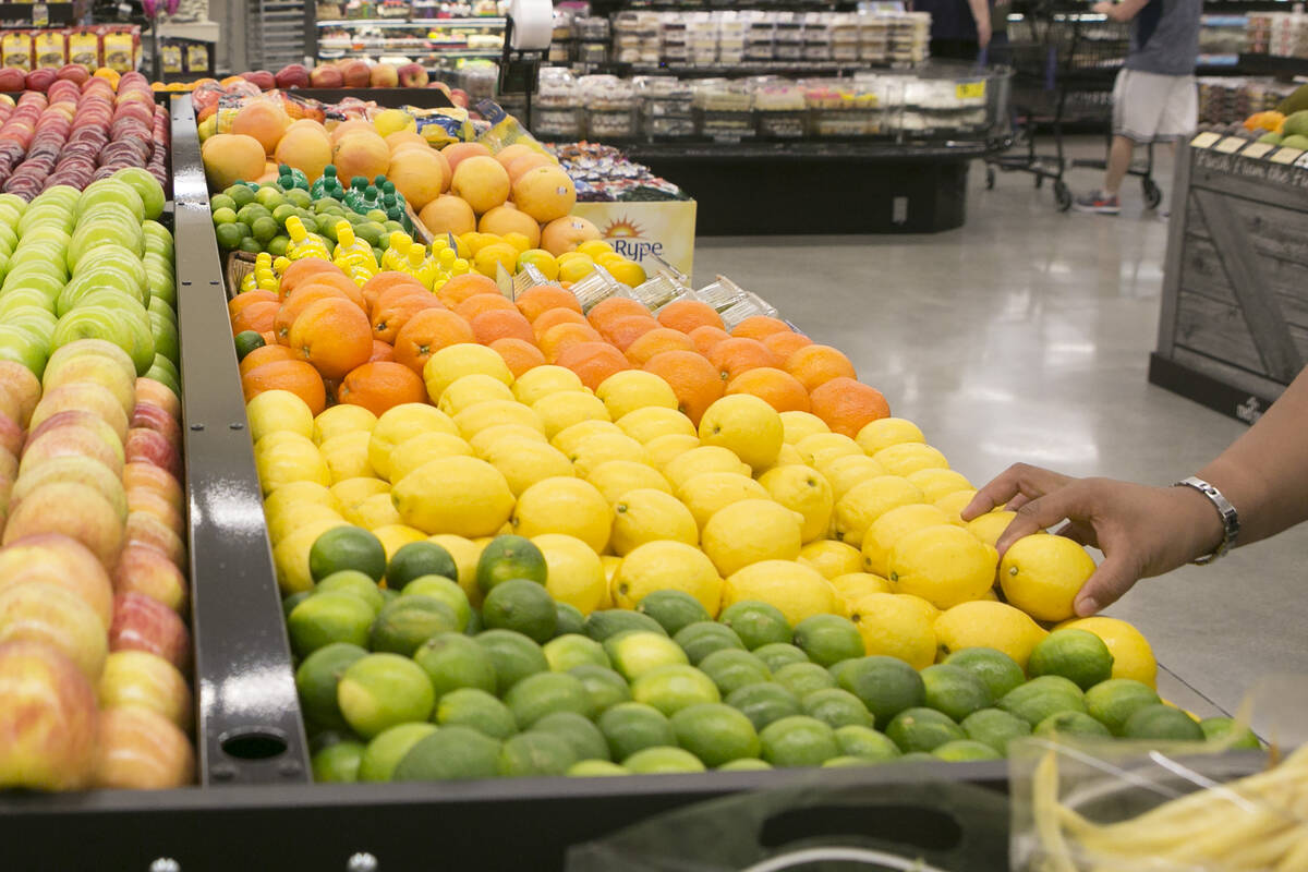 A customer grabs a lemon while browsing through produce during the grand opening of Albertsons ...