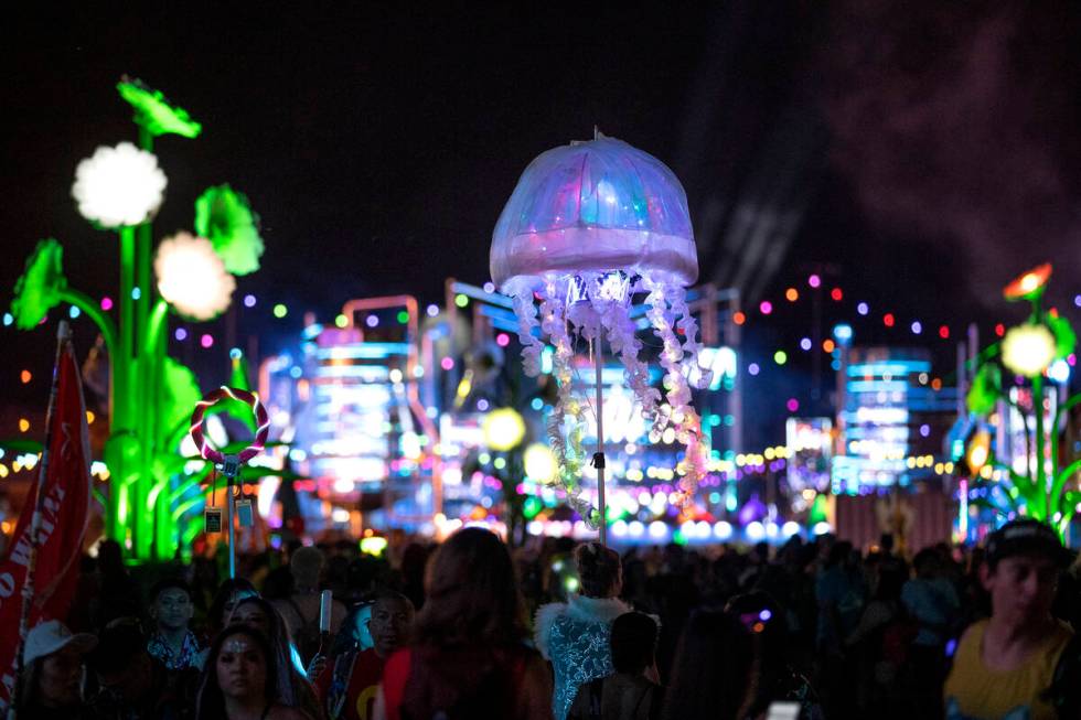 An attendee leads their group through the crowd with a jellyfish umbrella during the second day ...