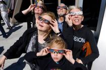 Sandra Callies, center left, and her husband, Gerard, center back, watch a partial solar eclips ...