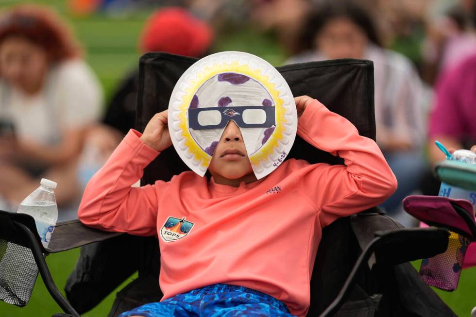 Yurem Rodriquez watches as the moon partially covers the sun during a total solar eclipse, as s ...