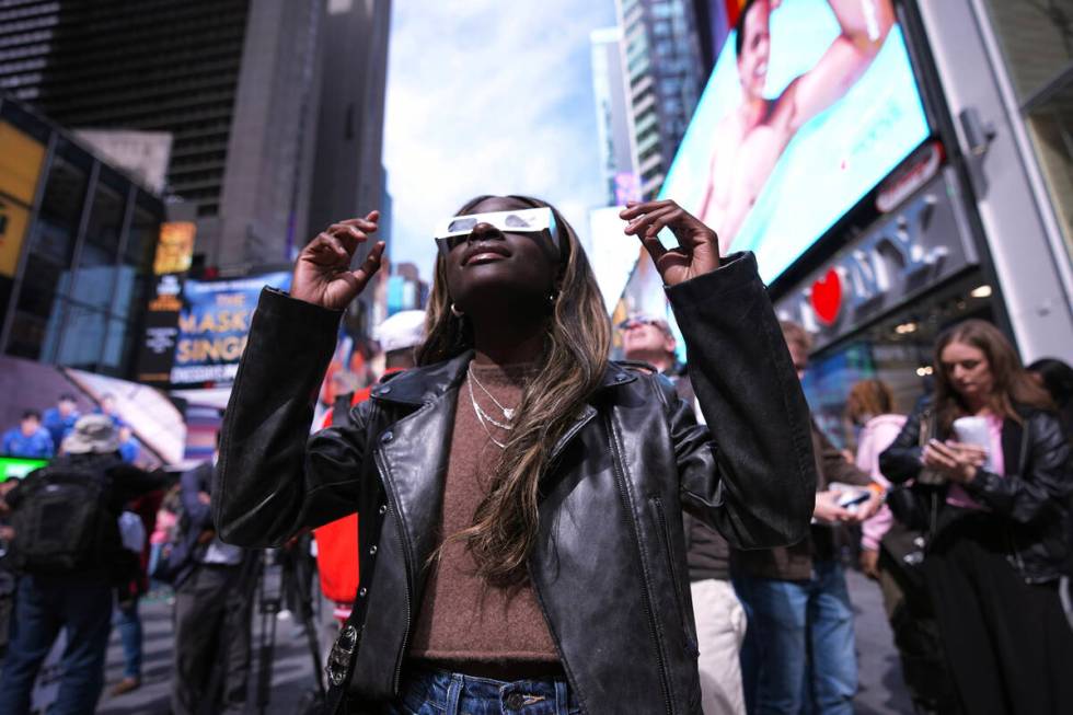 A woman views the solar eclipse in Times Square, Monday, April 8, 2024, in New York. (AP Photo/ ...