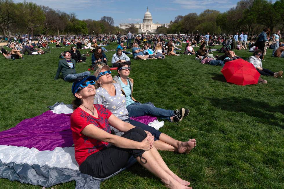 People wear protective glasses as they gather to watch as the moon partially covers the sun dur ...