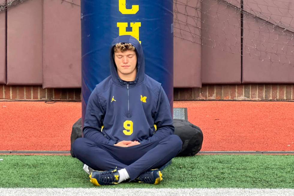 Michigan quarterback J.J. McCarthy sits on the field with his back against a padded goalpost on ...