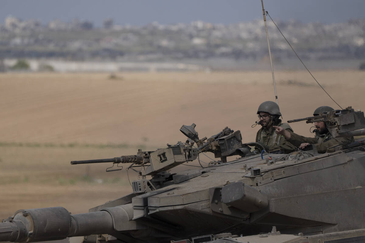 Israeli soldiers move on the top of a tank near the Israeli-Gaza border, as seen from southern ...