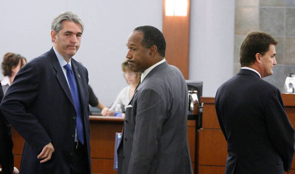 Former NFL player O.J. Simpson is flanked by his attorneys Gabriel Grosso, left, and Yale Galan ...