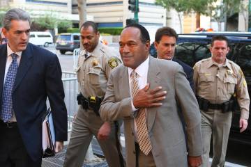 Escorted by court marshals, O.J. Simpson, center, is accompanied by his attorneys Gabriel Grass ...