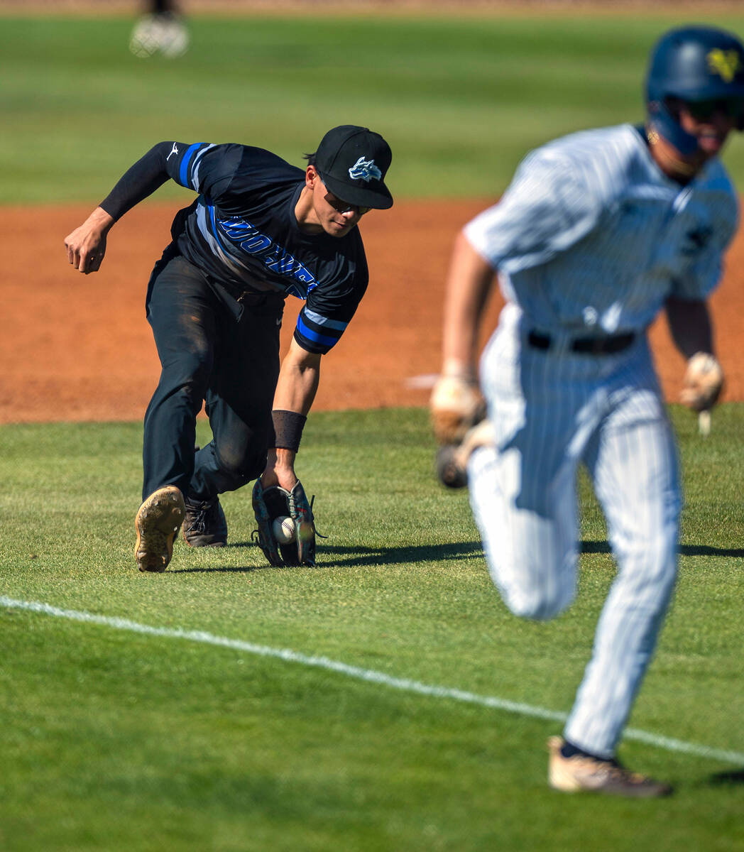 Basic third baseman Lyndon Lee looks to scoop up a ground ball as a Spring Valley runner scores ...