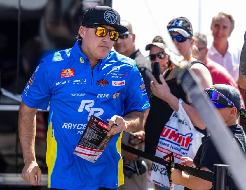 Top Fuel racer Tony Stewart signs autographs in his pit before his first race of the day during ...