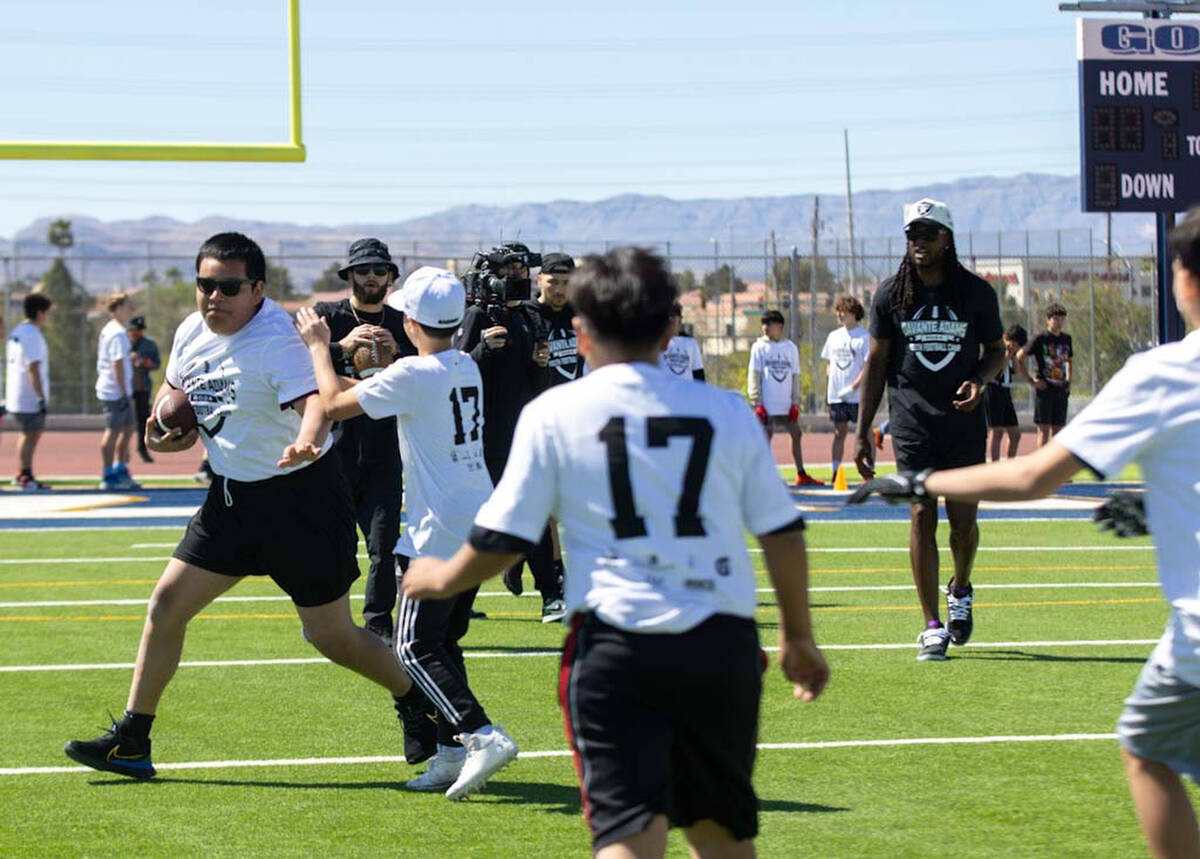 Raiders wide receiver Davante Adams, back right, looks on as a participant of his youth camp ru ...