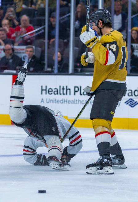 Golden Knights defenseman Nicolas Hague (14) checks Chicago Blackhawks center Connor Bedard (98 ...