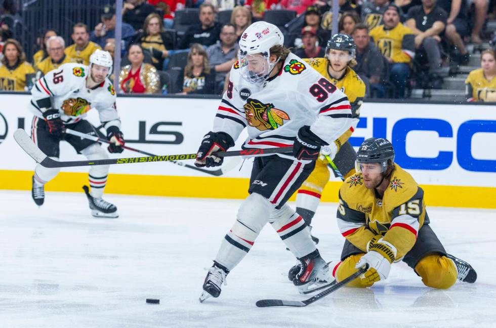 Golden Knights defenseman Noah Hanifin (15) pokes the puck away from Chicago Blackhawks center ...