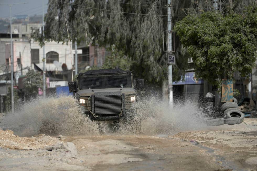An Israeli military vehicle drives through water during a military operation in the nearby Nur ...