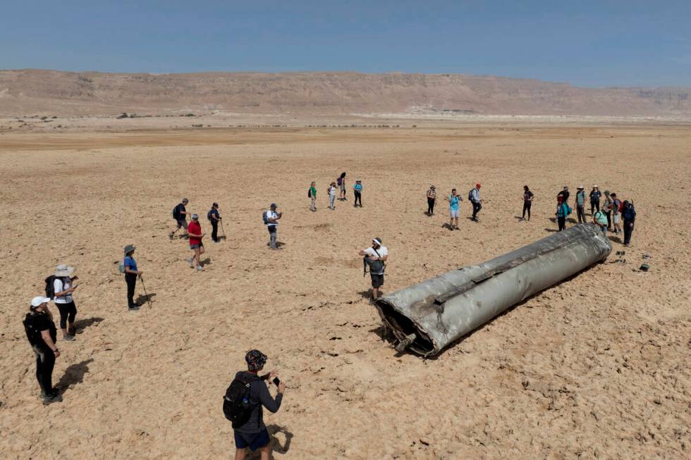 People gather around a component from an intercepted ballistic missile that fell near the Dead ...