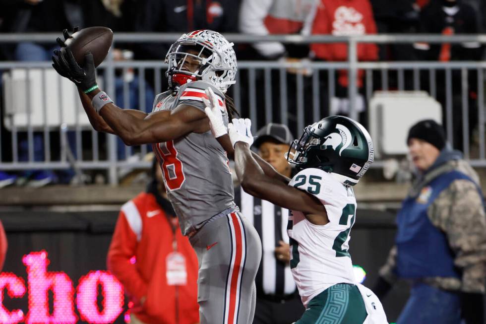 FILE - Ohio State receiver Marvin Harrison, left, catches a touchdown pass over Michigan State ...