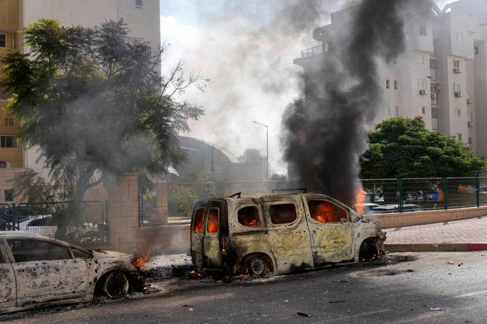 FILE - Cars are on fire after they were hit by rockets from the Gaza Strip in Ashkelon, Israel, ...