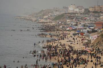 Palestinians spend the day on the beach along the Mediterranean Sea during a heatwave in Deir a ...