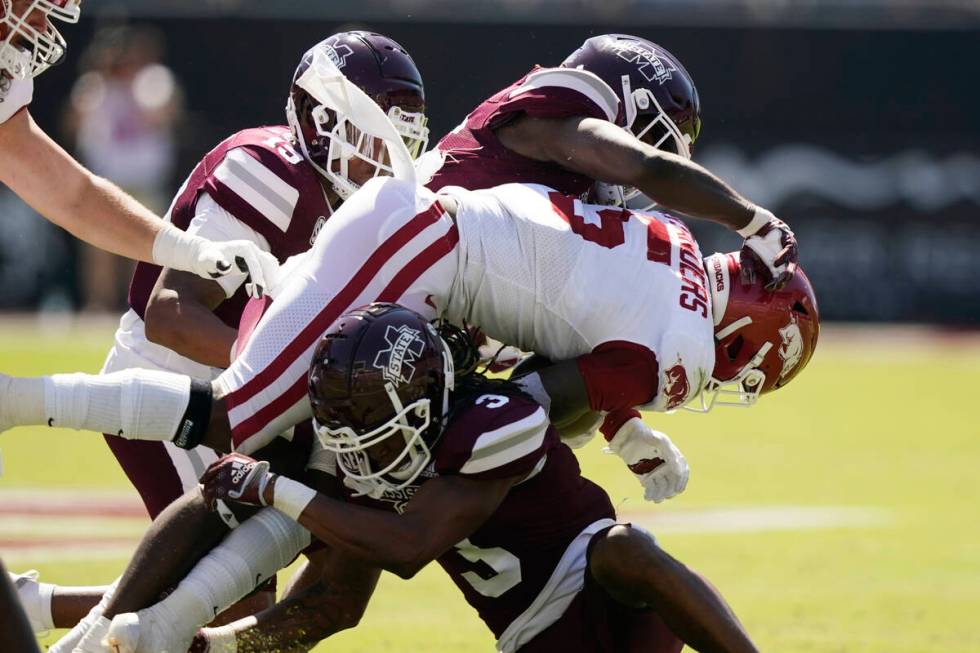 Arkansas running back Raheim Sanders (5) is tackled by a couple of Mississippi State defenders ...