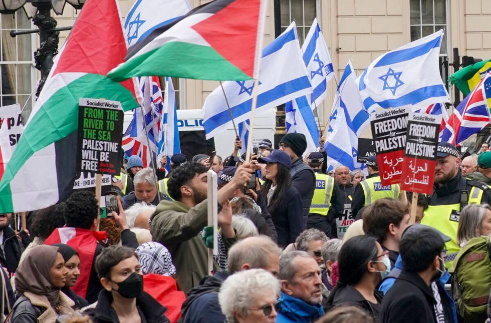 People take part in a pro-Palestine march as they walk past a counter protest with Israeli flag ...