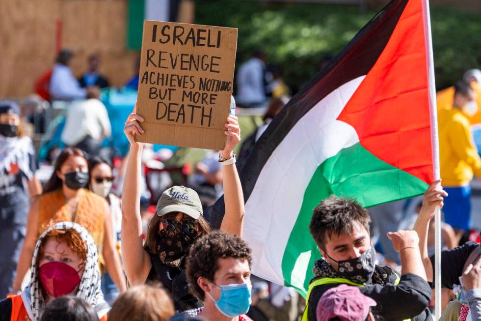 Pro-Palestinian supporters hold up a sign and flag inside an encampment on the UCLA campus Frid ...