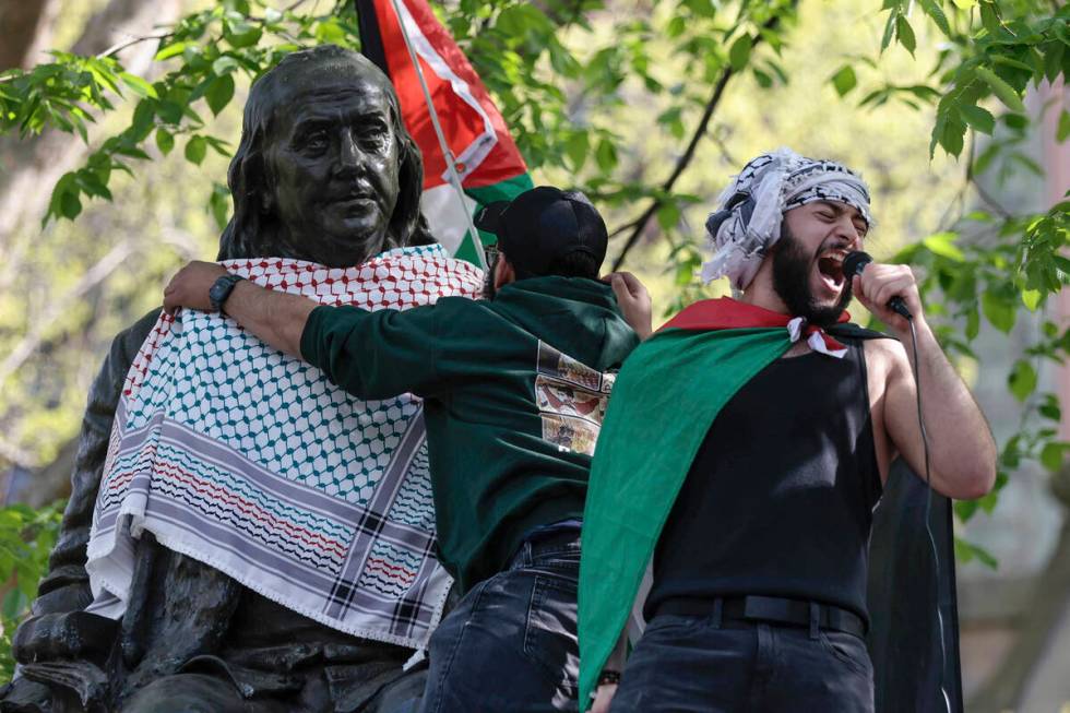 Qais Dana protests as a person puts a scarf on a Ben Franklin statue on Penn's campus during a ...