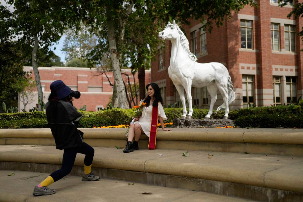 A recent graduate has their photograph taken in front of the school's mascot on the USC campus ...
